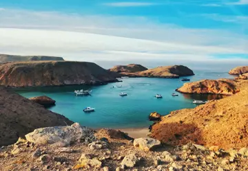 1 brown and green rock formation on blue sea under blue sky during daytime