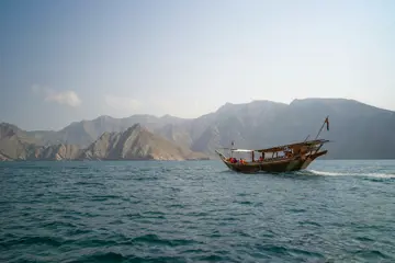 an omani dhow sailing across fjords in musandam oman